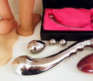 Stainless steel sex toys, including njoy Pure Wand, njoy Pure Plug, Ballistic Metal steel egg, and Fifty Shades of Grey silver pleasure balls