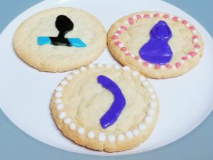 3 cookies. One cookie with a turquoise bullet inside the We-Vibe Dusk sleeve, one with a We-Vibe Touch, and one with a We-Vibe Rave