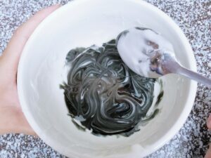 Swirling black food coloring on white sugar cookie icing