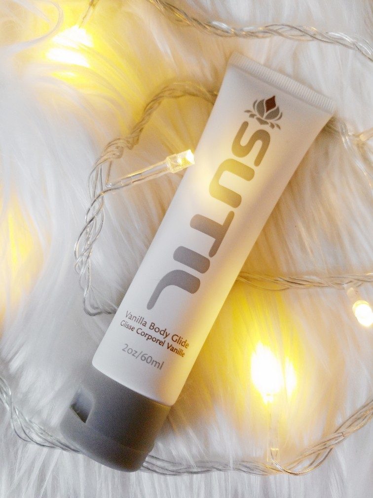 Hathor / SUTIL Body Glide vanilla flavour lube tube on white fur amid warm white LED lights
