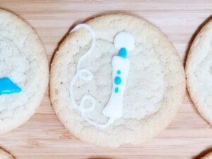 A sex toy cookie decorated with the Hitachi Magic Wand rechargeable and its cord in whimsical loops.