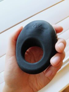 Photo of me holding the Hot Octopuss Atom vibrating cock ring in my hand. It has a raised contour to fit between the labia, against the clitoris.