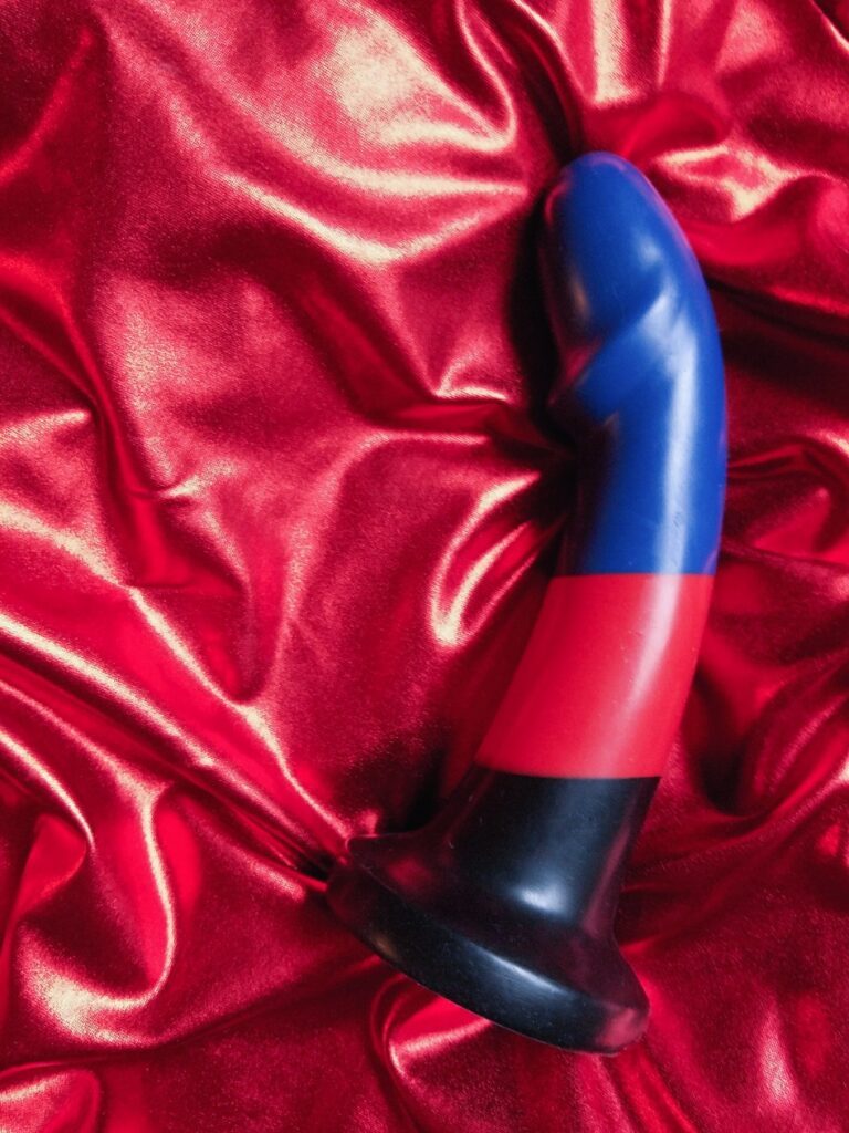 BS Max Poly Pride striped silicone dildo on red metallic fabric bacground