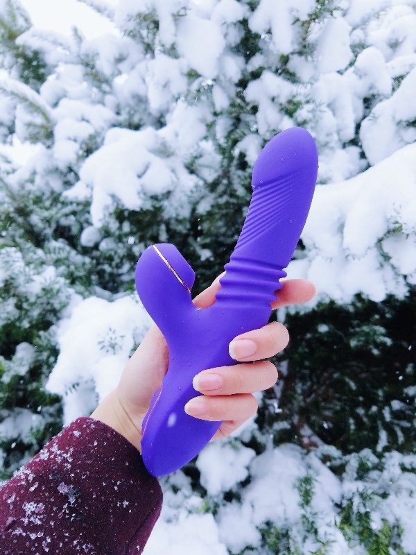 [Image: holding the Blush Novelties Lush Iris rabbit vibrator outside in front of a snow-covered evergreen tree.]