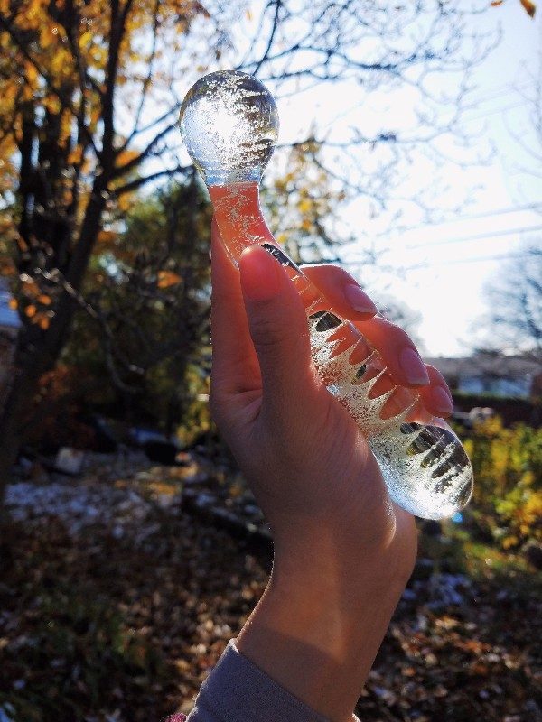 [Image: Clear Glow-in-the-Dark NS Novelties G-Spot/A-Spot Glass Dildo in my hand in the sun. The forward angling and bulbous head make this one of the best A-spot dildos]
