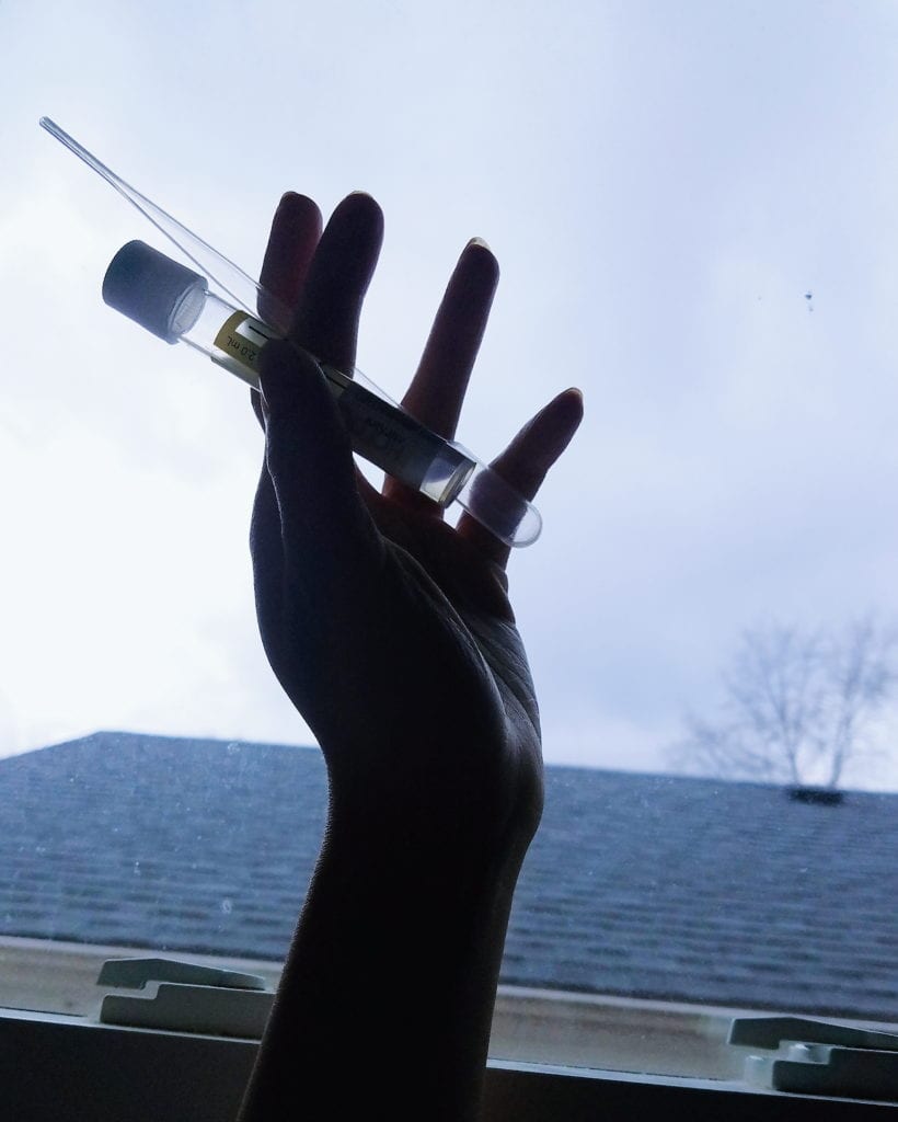 [Image: my silhouetted hand holding the sample vial and pipette included in the LetsGetChecked at-home / mail-in STI test kit]