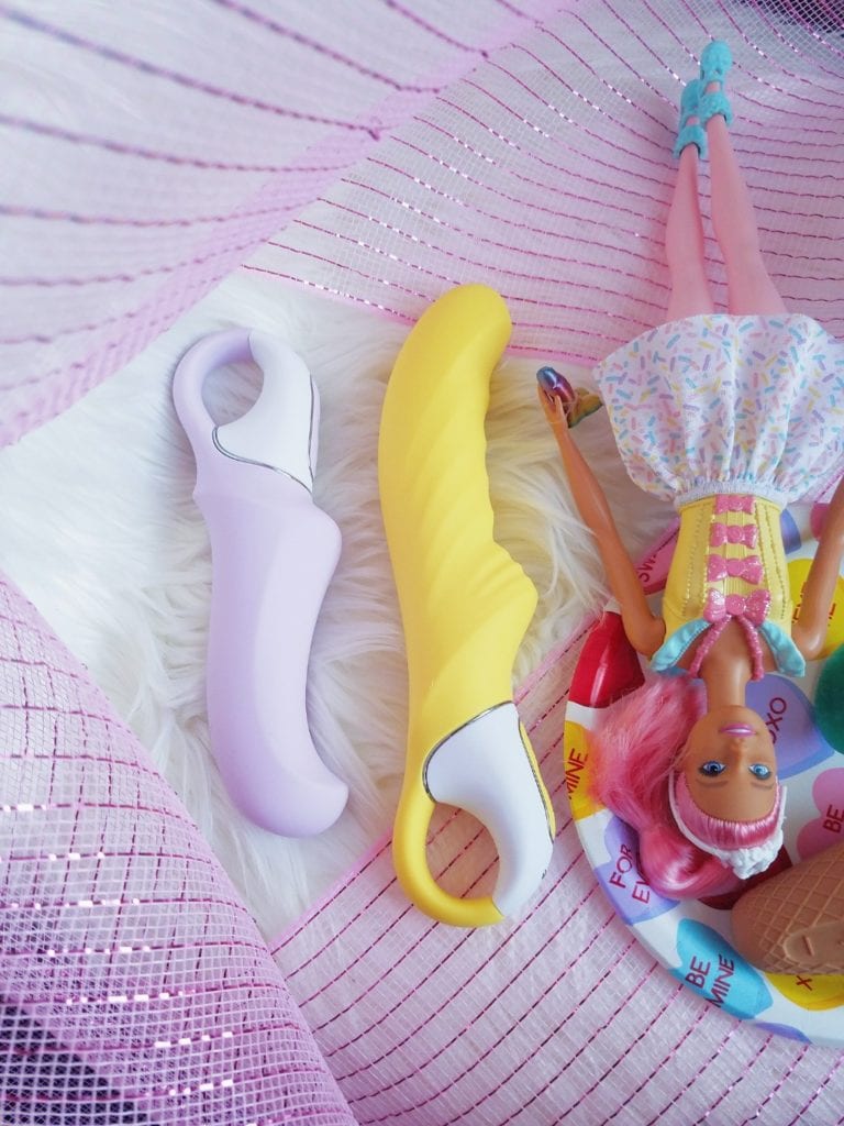 [Image: side view of the Satisfyer Charming Smile and Yummy Sunshine next to Barbie doll lying down]