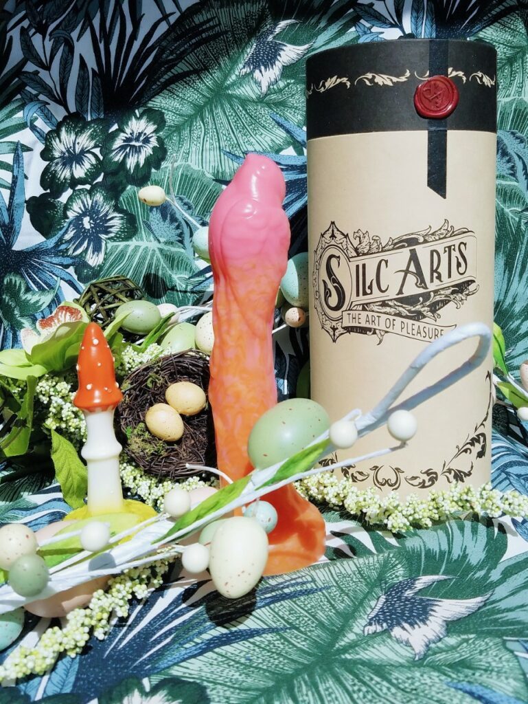 [Image: Self Delve Amanita Muscaria / Fly Agaric textured mushroom butt plug / dildo next to orange and pink Silc Arts Sparrow and Silc Arts cardboard canister packaging.]
