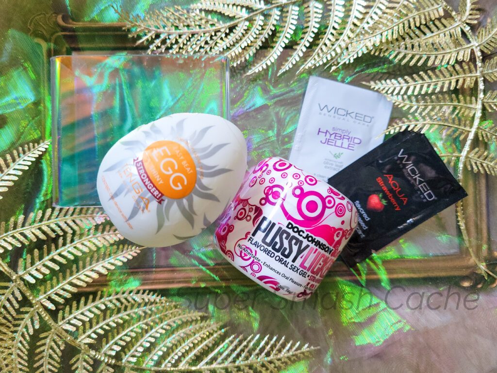 Left to right: Tenga Easy Beat Egg, a jar of Doc Johnson's PUSSY LICKER flavored oral sex gel, and packets of Wicked Hybrid Jelle and Wicked Aqua Strawberry lube