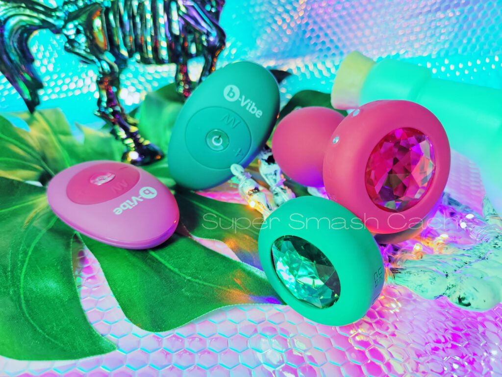 b-vibe sparkling vibrating jewel plugs with rhinestone bases and remote controls in pink ruby and emerald