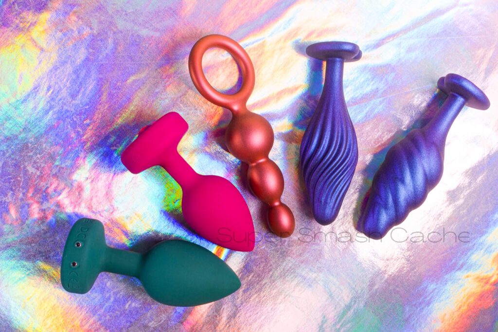 Left to right: b-Vibe vibrating jewel plug M/L Emerald, S/M Pink Ruby, Anal Adventures Beaded plug in color morph copper, Matrix Swirled and Bumped princess plugs with heart-shaped base
