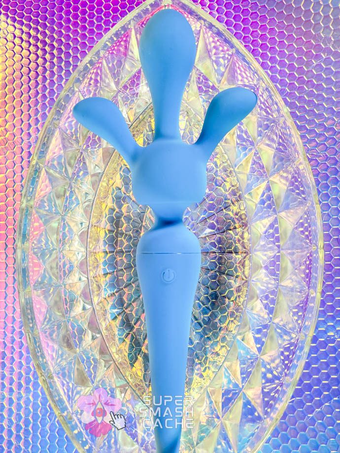 A blue California Exotics Couture Collection silicone wand with a triple penetration attachment on a crystal plate shaped like a vulva
