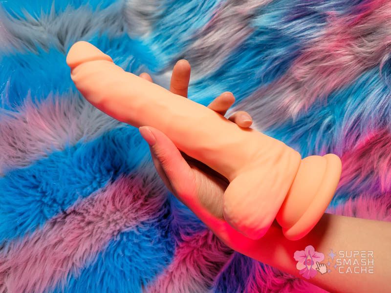 A hand holding a silicone dildo