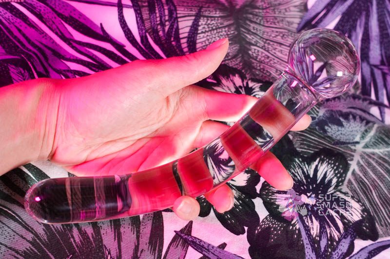 Hand holding a shallow curved glass dildo from Luscious Playthings