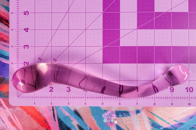 Dillenia Gama Review: 9.7" Glass Glizzy for Dreamy Deep Dicking 3 JimmyJane Dillenia Gama glass dildo laid on inch grid matboard showing 9.7-inch total length, 1.5-inch maximum diameter at larger bulb, and 1.1-inch diameter at smaller bulb. S-curve design visible against measurement grid