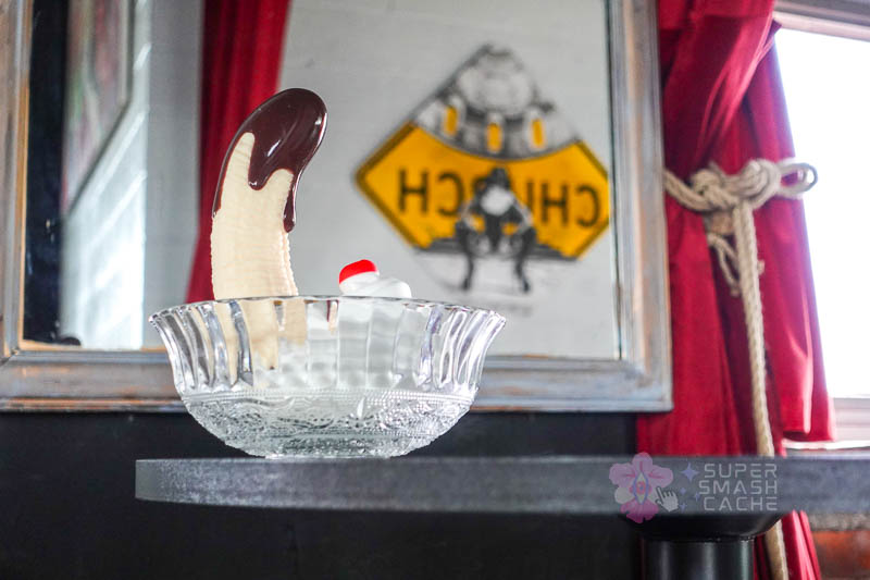 XR Brands Simply Sweet Chocolate Dipped Banana Split suction cup dildo in front of a mirror